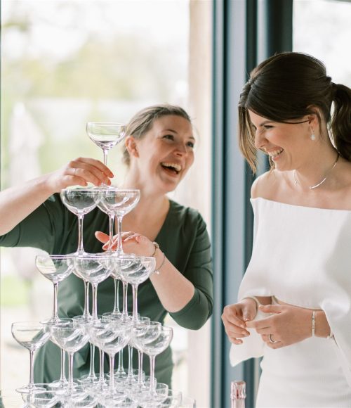 Drink The Moment Jennifer de Ru showing bride how to build a champagne tower
