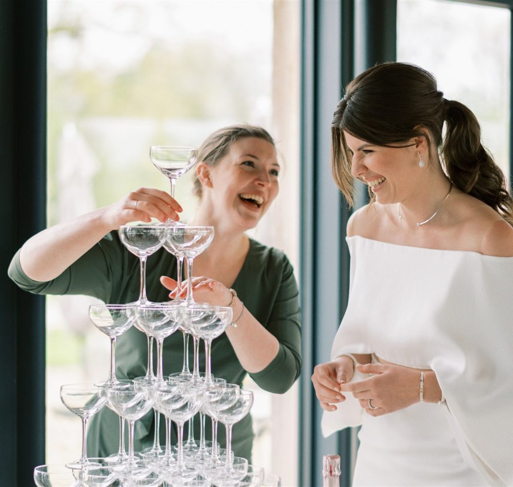 Drink The Moment Jennifer de Ru showing bride how to build a champagne tower